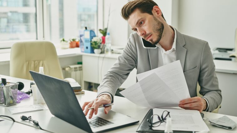 Busy young office worker in formalwear consulting client on mobile phone
