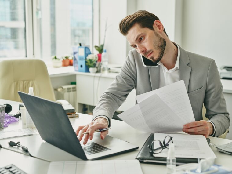 Busy young office worker in formalwear consulting client on mobile phone