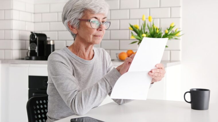 Middle Aged Woman Reading Financial Letter Document Attentively