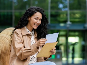 Woman reading a letter outdoor, relaxed setting with nature backdrop
