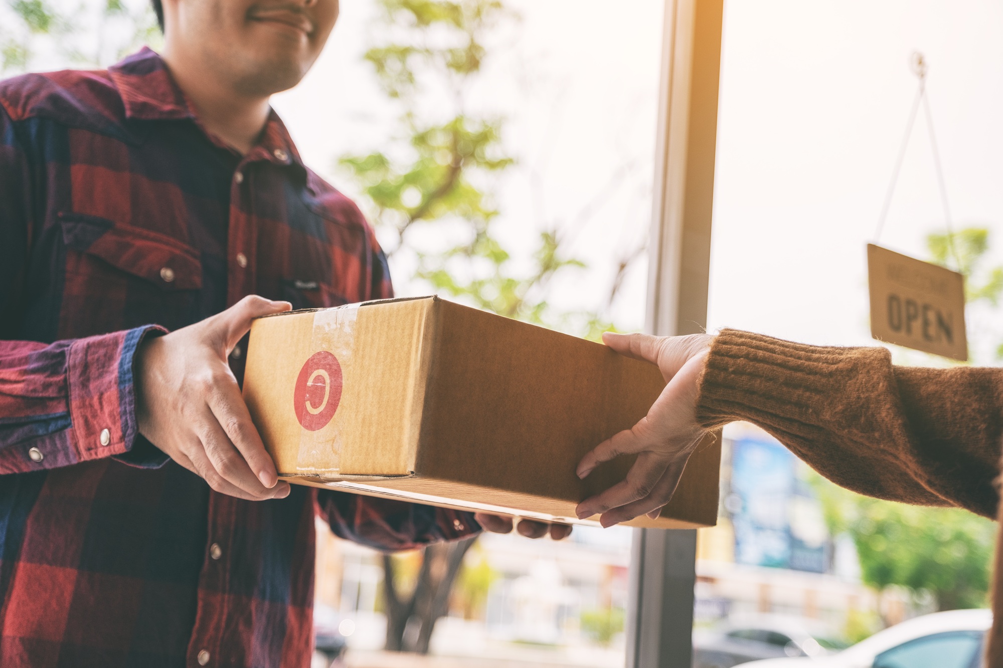 woman receiving parcel box from delivery man at the house's door